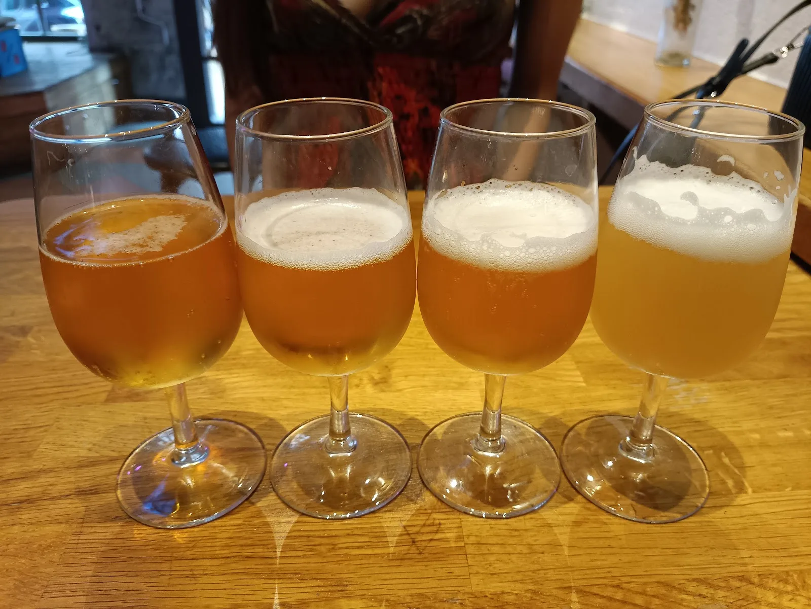 Quatre petits verres de dégustation remplis de bières ambrées, posés sur une table en bois à L'Instant T